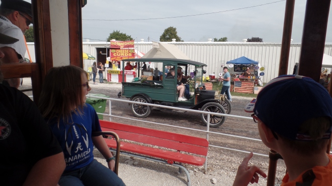 People riding on a trolley see a restored truck