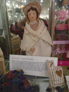 Part of a display case showing a doll and a stuffed cat